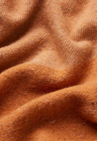 A close-up of draped camel-colored wool fabric with a soft, brushed texture.