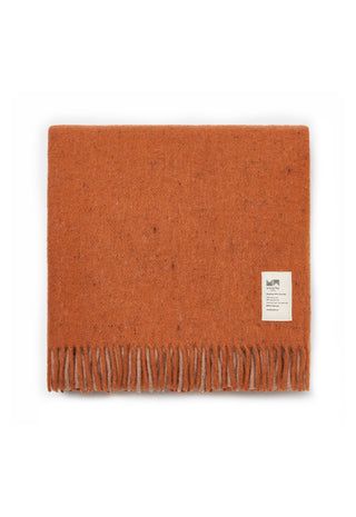 A folded orange-brown wool scarf with fringe on one end and a small white brand label, photographed on a clean white background.
