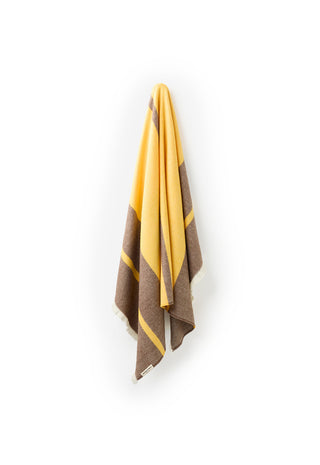 A folded striped scarf in yellow and brown hangs against a plain white background.