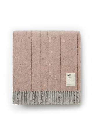 A folded dusty pink knit throw blanket with vertical ribbed stripes and fringed edges, featuring a small white woven label on the right side, set against a plain white background.